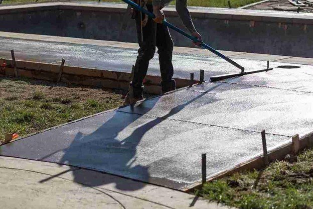 Concrete driveway installation with a worker smoothing freshly poured surface using a finishing tool in Beachwood, OH