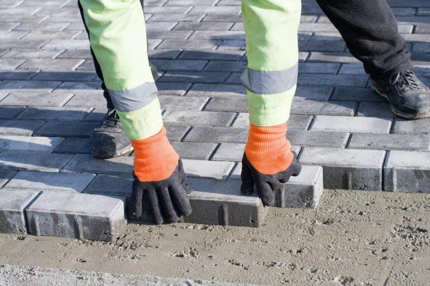 Concrete contractor placing brick pavers by hand for residential driveway installation in Shaker Heights, OH