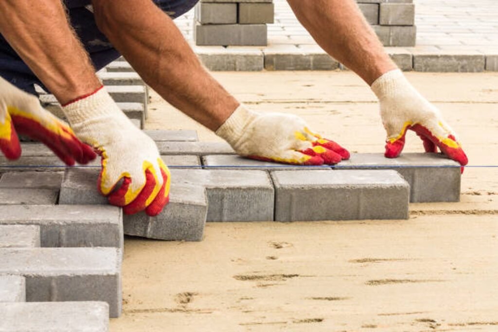 Contractor installing concrete pavers for patio construction on a leveled sand base in Beachwood, OH