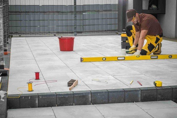 Contractor using a level tool to align large concrete patio slabs during installation in Shaker Heights, OH