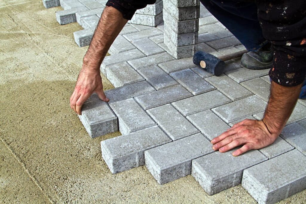 Contractor installing concrete pavers for patio construction on a compacted base in Beachwood, OH
