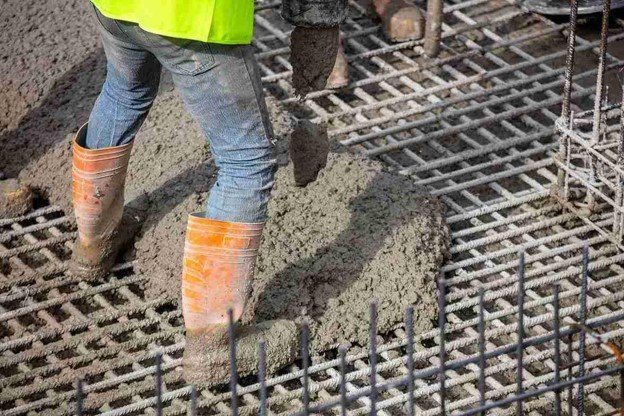 Worker pouring fresh concrete over steel rebar grid for structural slab construction in Shaker Heights, OH