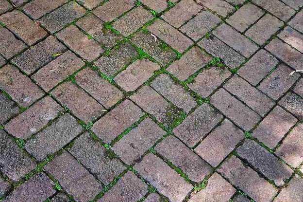 Uneven patio surface with shifting pavers and gaps before concrete patio replacement in Beachwood, OH